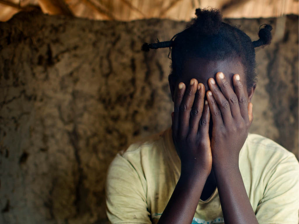 DRC. Dungu. Eine junge Frau versteckt ihr Gesicht während sie in ihrer Hütte in einem Flüchtlingslager am Stadtrand von Dungu, im Nordosten der DRC fotografiert wird. Die junge Frau war von den Rebellen der LRA ( Widerstandsarmee des Herren) entführt worden als sie erst 14 war und ist nun Mutter als Folge einer erzwungenen Beziehung im Busch. Erst durch die Bekanntschaft mit Sister Angelique Namaika, der Gewinnerin des diesjaehrigen Nansen Refugee Awards der UNHCR, die sich um von der LRA  missbrauchte Frauen und Mädchen kuemmert, nimmt sie nun an Näh-und Kochkurse teil und kommt langsam ins Leben zurueck.  09.07.2013 © 2013 Anne Ackermann