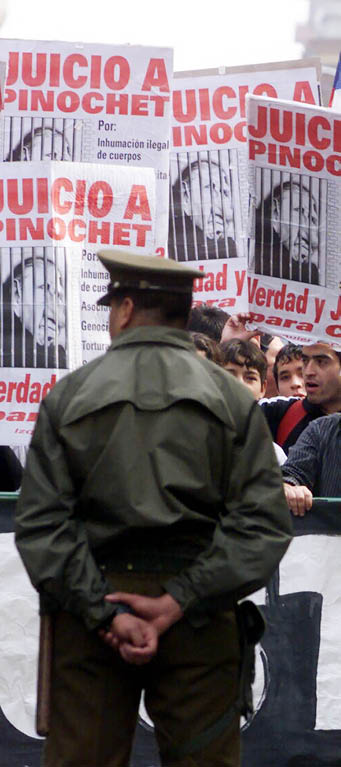 A police officer stands guard in front of people protesting against General Augusto Pinochet outside the Supreme Court in Santiago, April 27. An appeals court opened a landmark hearing on April 26 that will decide whether Pinochet can be stripped of immunity and put on trial for alleged human rights abuses during his 1973-1990 rule. The headline on the signs read:"Trial for Pinochet; Truth and Justice." - RTXJQT8