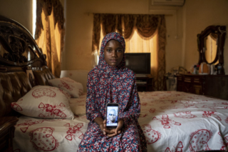 Bintu Tunkara, daughter of Lamin Tunkara, who she never got a chance to meet, looks at a picture of him on her phone. Her mother Adama Conteh was seven months pregnant with her when Lamin was murdered. He was the only Gambian among a group of over 50 Ghanaians and other West African migrants bound for Europe in 2005 by the sea. ©Jason Florio / TRIAL International